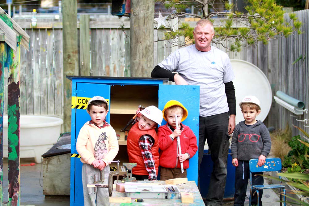 Jason gardiner team with the kids in front of tool shed