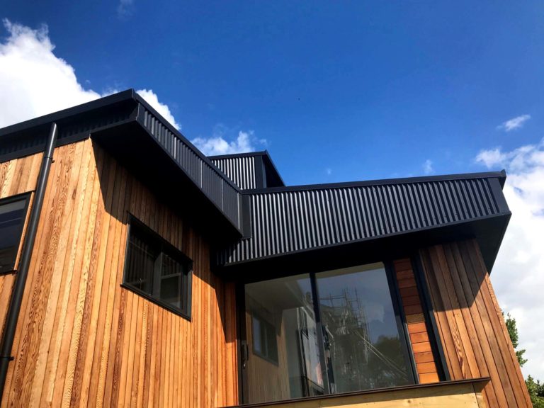 Wooden paneled new build with black corrugated roof